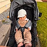 baby, infant, stroller, sleeping, outdoor, cap, overalls, corduroy, gray_clothing, harness, baby_toys, rattle, grass, walkway, house, garden, portrait, sitting, feet, family_outing