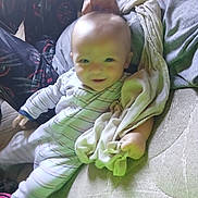 Michael joined the competition — help win amazing prizes! baby, child, blanket, pajamas, striped_clothing, hand, adult, mischief, bunny_ears, mattress, indoor, smiling, person, couch, playful, cute, comfort, family, relaxing, soft