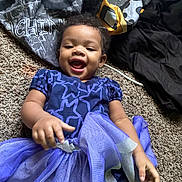 Khloe Grace joined the competition — help win amazing prizes! baby, blanket, blue_dress, carpet, child, clothing, cute, fabric, fun, happy, indoor, infant, lying_down, person, playful, portrait, smiling, star_pattern, toddler, tulle_skirt