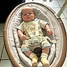 baby, infant, child, bouncer, baby_seat, harness, toy, elephant_toy, portrait, lying_down, indoor, tiled_floor, nursery, clothing, onesie, socks, smiling, face, furniture, safe