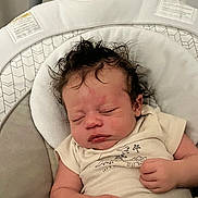 Dawson is registered to the contest to win money with this photo: baby, sleeping, infant, onesie, dinosaur_print, cushion, baby_seat, curly_hair, peaceful, closed_eyes, newborn, soft_fabric, hand, cute, indoors, portrait, resting, child, cozy, toddler