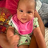 Laura joined the competition — help win amazing prizes! baby, infant, child, pink_bib, green_onesie, minnie_mouse, person, arm, foot, indoor, pillow, adult, red_shirt, curious, playful, portrait, closeup, skin, face, couch