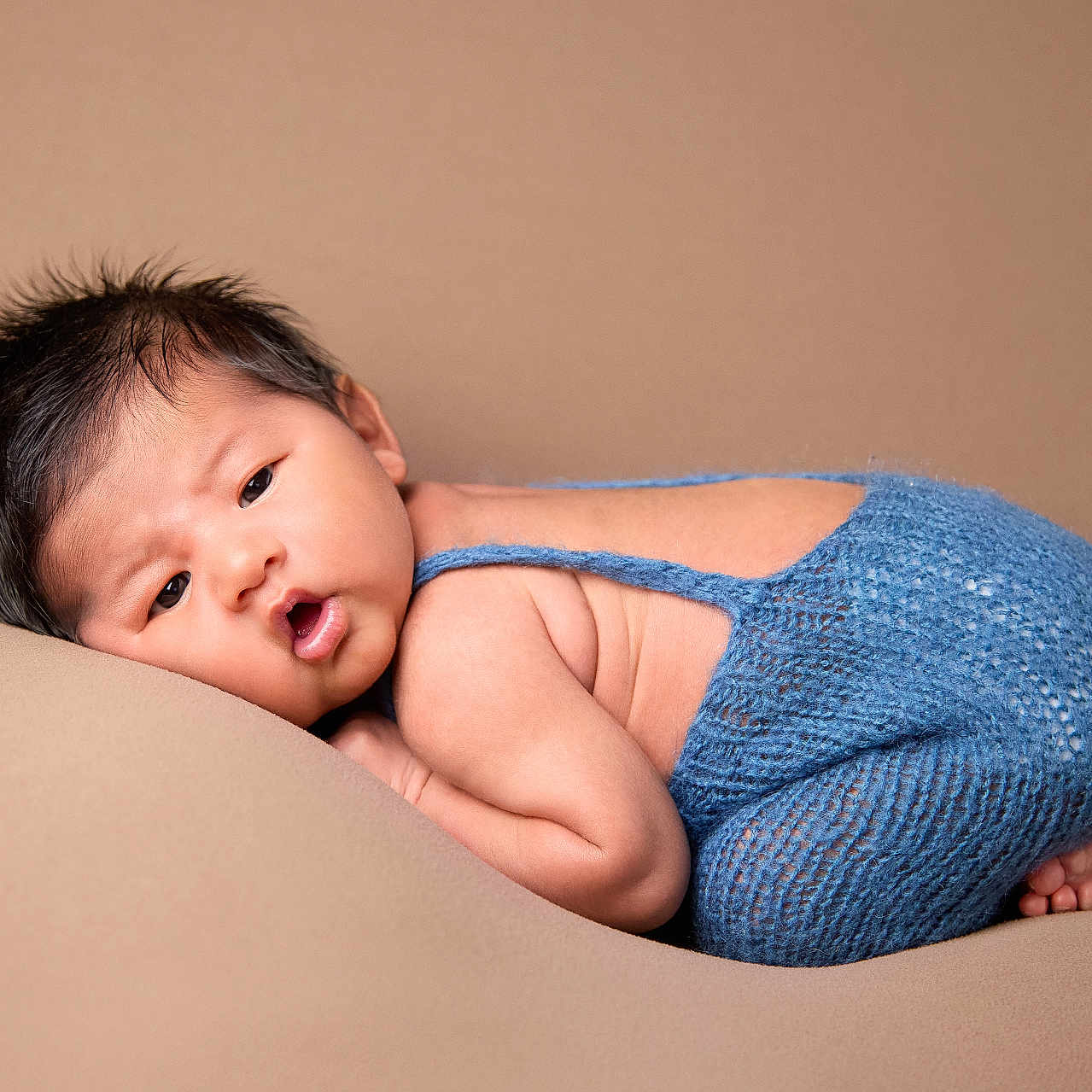 Jaycob is registered to the contest to win money with this photo: baby, beige_background, blue_outfit, child, chubby_cheeks, cozy, curly_hair, cute, expression, face, indoors, infant, knitted_clothing, lying_down, newborn, portrait, resting, skin, small_feet, soft_texture