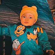 Jordan joined the competition — help win amazing prizes! baby, child, bed, blue_bedspread, yellow_hat, disney_characters, mickey_mouse, donald_duck, pluto, clothing, sweater, pants, indoor, portrait, infant, cute, lying_down, person, face, headwear
