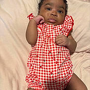 Nova is registered to the contest to win money with this photo: baby, infant, child, red_checkered_outfit, strawberry_prints, blanket, soft_texture, lying_down, cute, curious_expression, hand_gesture, portrait, indoors, skin, face, head, legs, photography, clothing, person