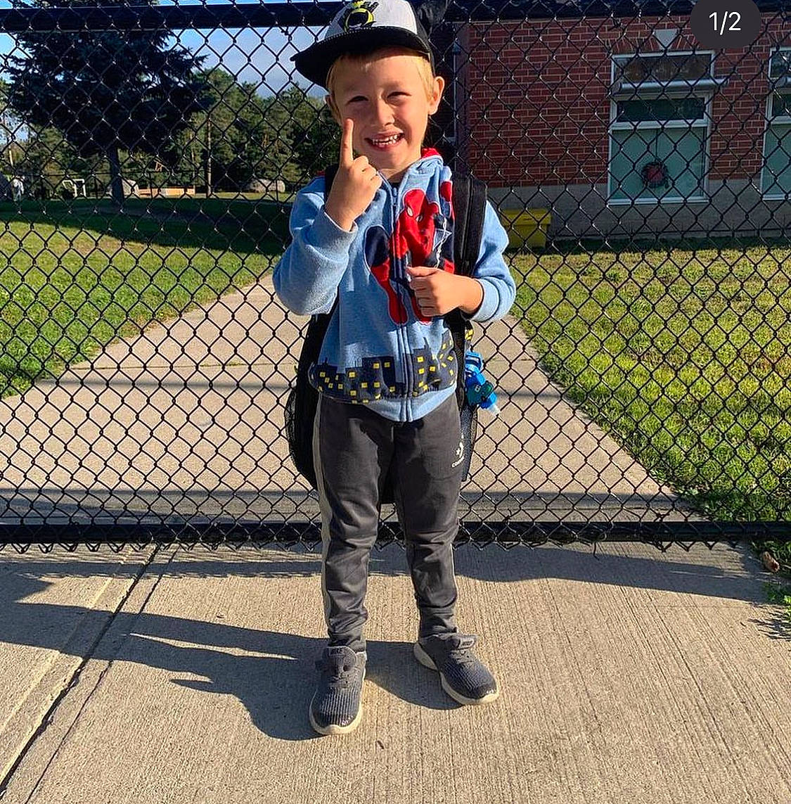 Richard is registered to the contest to win money with this photo: asphalt, cap, chain_link_fencing, denim, electric_blue, fence, fun, grass, hat, joy, leisure, mesh, net, pattern, person, recreation, sleeve, smile, toddler, tree
