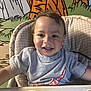 toddler, child, high_chair, smiling, gray_tshirt, nike_logo, indoor, colorful_background, cartoon_mural, happy, face, short_hair, portrait, baby, seated, clothing, person, cute, playful, expression