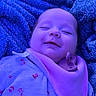 Lakelyn is registered to the contest to win money with this photo: baby, sleeping, blanket, bib, pacifier, infant, cozy, soft_light, purple_tone, smiling, face, child, cute, clothing, resting, indoors, portrait, peaceful, young, relaxed