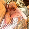 Lakelyn is registered to the contest to win money with this photo: baby, sleeping, pacifier, tattoo, hand, blanket, pink_clothing, face_sticker, indoor, person, comfort, soft_lighting, cozy, infant, rest, couch, holding, relaxation, cute, family