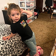 Aylani is registered to the contest to win money with this photo: toddler, child, indoor, leopard_print, bedspread, pink_slippers, teddy_bear_slippers, carpet, clothing, storage_drawers, toy, person, cute, posing, hair_tied, black_shirt, pants, furniture, room, door