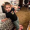 toddler, child, indoor, leopard_print, bedspread, pink_slippers, teddy_bear_slippers, carpet, clothing, storage_drawers, toy, person, cute, posing, hair_tied, black_shirt, pants, furniture, room, door