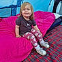 Cassie-Mai is registered to the contest to win money with this photo: toddler, child, smiling, sitting, tent, camping, sleeping_bag, pink, blue, leggings, strawberry_pattern, shirt, white_shoes, plaid_blanket, indoor, cozy, happy, person, footwear, fabric
