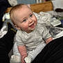 baby, child, smiling, happy, sitting, indoors, soft_clothing, socks, face, cute, infant, portrait, young_child, cozy, warm, blurry_background, light_skin, short_hair, casual_wear, person