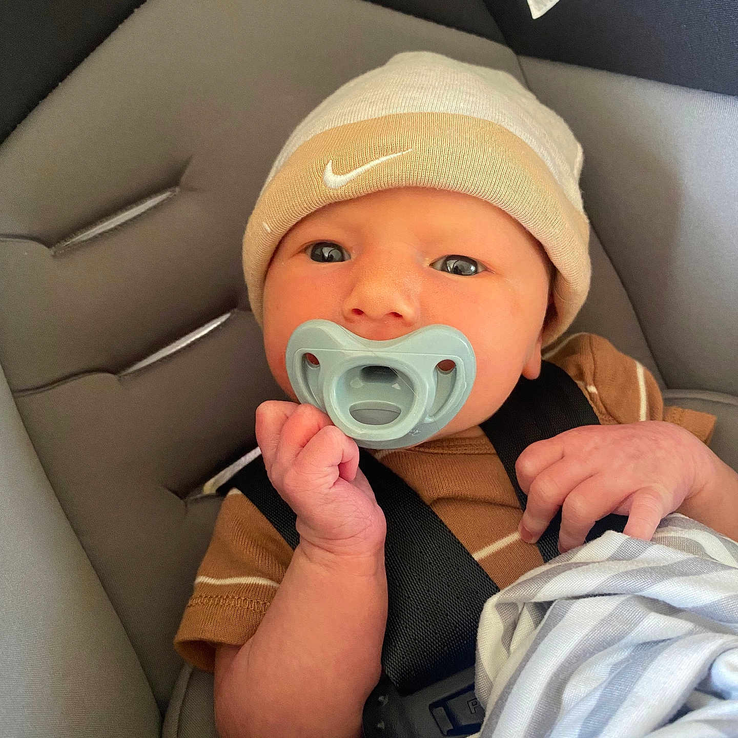 Grayson is registered to the contest to win money with this photo: baby, beanie, blanket, car_seat, child, clothing, comfort, cute, face, hand, indoors, infant, newborn, pacifier, person, portrait, safety, sitting, straps, young_child