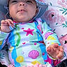 baby, infant, child, portrait, smiling, sun_hat, colorful_clothing, seashell_pattern, floral_blanket, outdoor, sitting, harness, pacifier_clip, barefoot, foot, hand, face, pink, playful, close_up