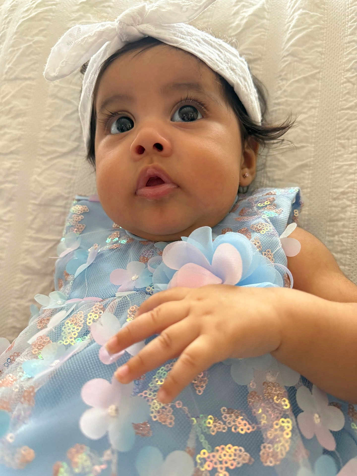 Ruth joined the competition — help win amazing prizes! baby, child, face, hand, headband, blue_dress, floral_pattern, sequins, curious, cute, portrait, infant, indoors, soft_light, closeup, young_child, adorable, skin, person, expression