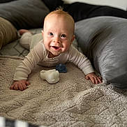 Miles is registered to the contest to win money with this photo: baby, smiling, crawling, blanket, pillow, toy, pacifier, indoor, infant, face, cute, happy, child, person, cozy, soft, clothing, head, hands, portrait