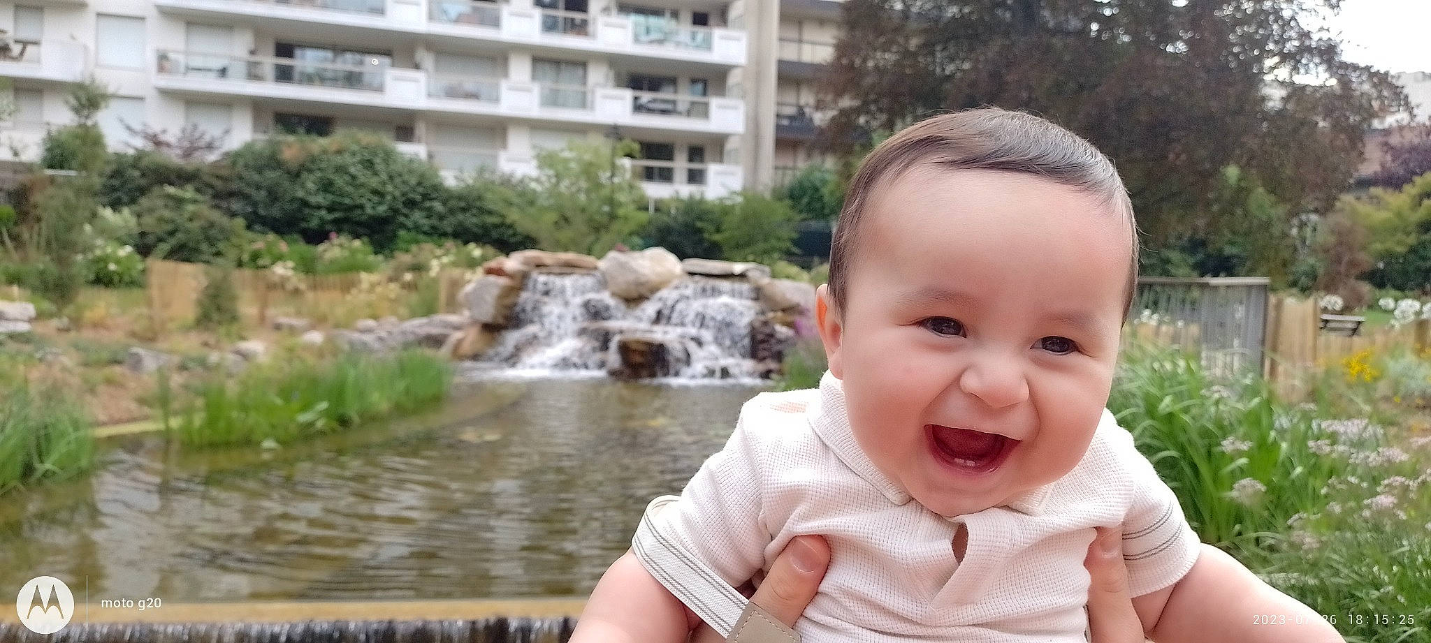 Mathias participe au concours pour gagner de l'argent avec cette photo : baby, baby_toddler_clothing, building, child, fun, grass, happy, lake, leisure, people_in_nature, person, plant, recreation, sitting, smile, t_shirt, toddler, tree, water, water_feature