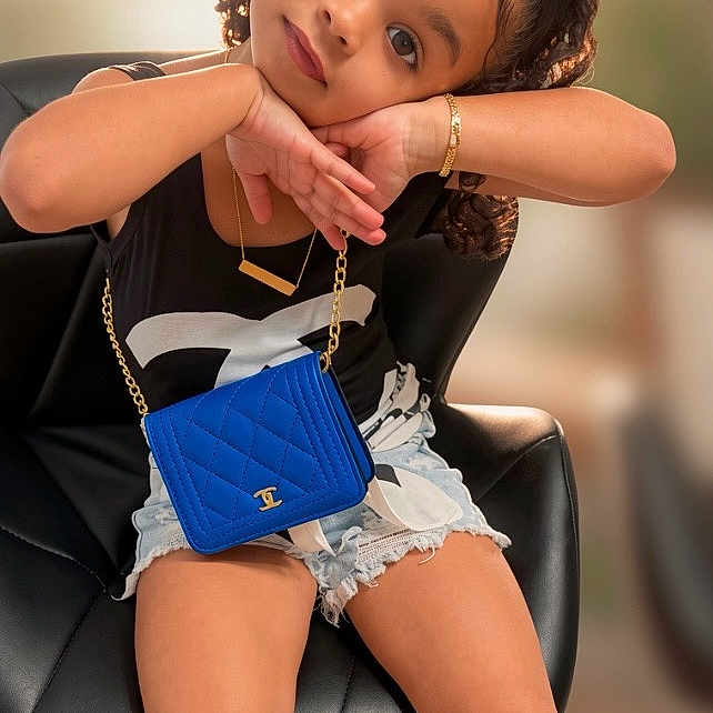 Cataleya Falcon joined the competition — help win amazing prizes! child, girl, curly_hair, black_top, denim_shorts, blue_purse, gold_bracelet, black_sandals, chair, posing, smiling, indoor, cute, fashion, accessories, portrait, young_child, sitting, casual, happy