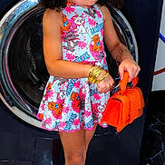 Cataleya Falcon is registered to the contest to win money with this photo: accessories, bracelets, child, colorful, curly_hair, cute, dress, fashion, floor_tiles, flower, girl, home, indoors, looking_down, orange_purse, orange_shoes, playful, standing, washing_machine, yellow_flower