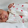baby, newborn, sleeping, onesie, hearts, infant, face, hand, clothing, bed, soft, peaceful, closeup, skin, person, cute, rest, child, portrait, sleep