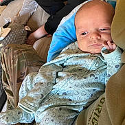 Aizen joined the competition — help win amazing prizes! baby, newborn, infant, onesie, animal_pattern, camo_pants, lap, blanket, bottle, indoor, person, resting, cute, clothing, face, hand, footwear, carpet, furniture, casual