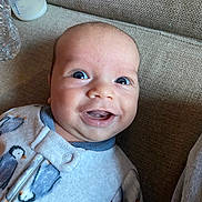 Aizen is registered to the contest to win money with this photo: baby, bottle, child, clothing, couch, cute, expression, face, furniture, happy, head, indoors, infant, onesie, penguin_pattern, portrait, skin, smile, water_bottle, young