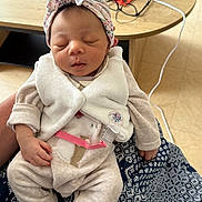 Inaya a rejoint le concours — aidez-le/la à gagner de superbes lots ! baby, infant, sleeping, headband, vest, onesie, hand, patterned_cloth, table, remote_control, glasses, pacifier_clip, floor, indoors, person, cute, peaceful, closeup, soft_fabric, resting