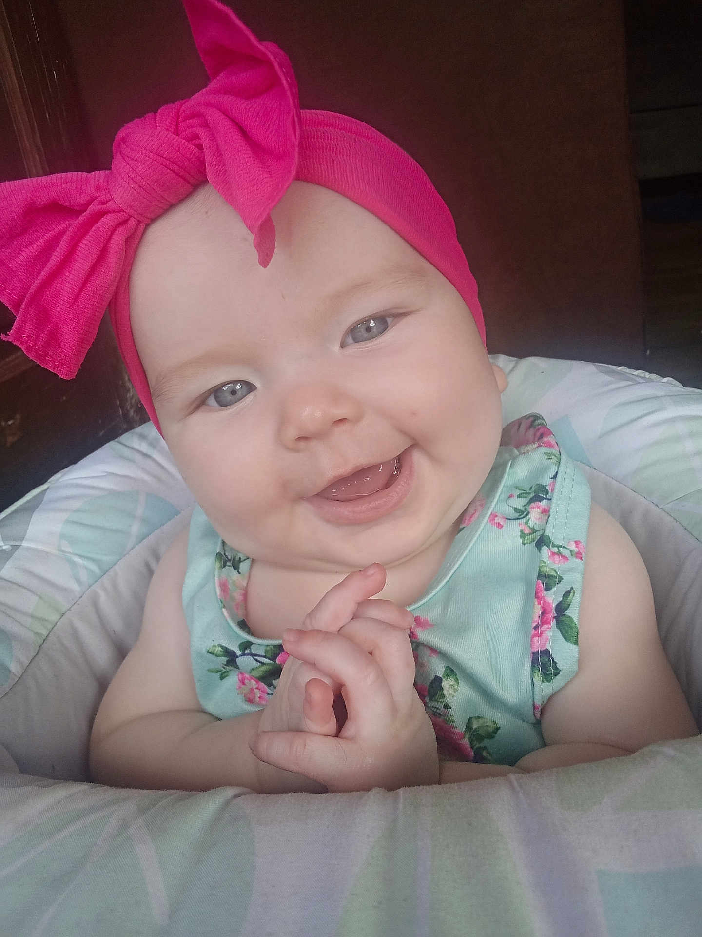 Eliana is registered to the contest to win money with this photo: baby, child, headband, pink, bow, smile, happy, hands, cushion, seat, floral, clothing, face, portrait, indoor, cute, infant, skin, expression, eyes
