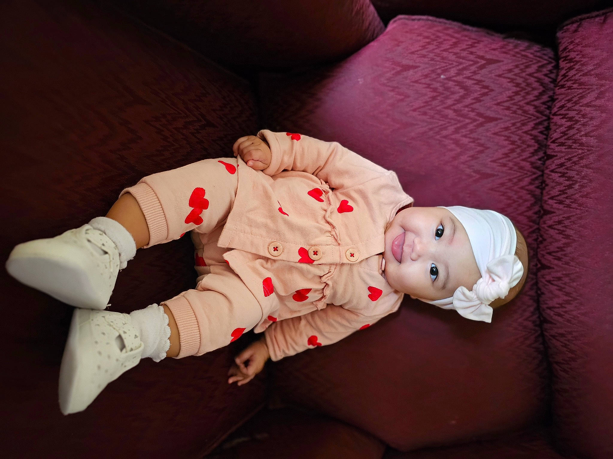 Rosie is registered to the contest to win money with this photo: baby, baby_toddler_clothing, carmine, child, comfort, eye, finger, flooring, foot, hat, head, headwear, human_body, human_leg, person, sitting, skin, sleeve, sock, thigh