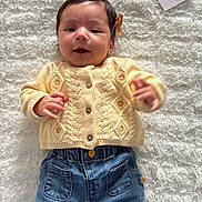 Yara participe au concours pour gagner de l'argent avec cette photo : baby, infant, child, yellow_sweater, denim_pants, knitted_slippers, bow, milestone_card, fluffy_blanket, lying_down, cute, smiling, indoor, portrait, closeup, happy, soft_texture, cozy, casual_clothing, baby_fashion