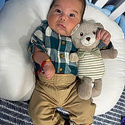 Yadiel joined the competition — help win amazing prizes! baby, plush_toy, teddy_bear, cushion, plaid_shirt, khaki_pants, brown_shoes, infant, cute, child, toy, bed, striped, bow_tie, bracelet, indoor, person, face, clothing, lying_down