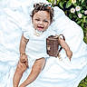 baby, child, smiling, curly_hair, headband, white_blanket, outdoor, greenery, flowers, purse, bracelet, necklace, happy, cute, infant, grass, nature, footwearless, fashion, portrait