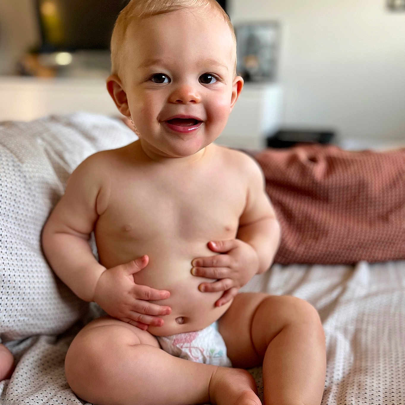 Léo participe au concours pour gagner de l'argent avec cette photo : baby, bed, blanket, child, cozy, cute, diaper, expression, face, hands, happy, indoors, infant, person, portrait, sitting, skin, smiling, toddler, young