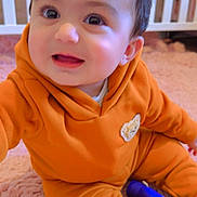 Muhammad is registered to the contest to win money with this photo: baby, child, orange_clothing, sitting, pink_rug, toy, flashlight, crib, indoor, smiling, happy, cute, infant, face, person, cozy, playful, soft, home, portrait