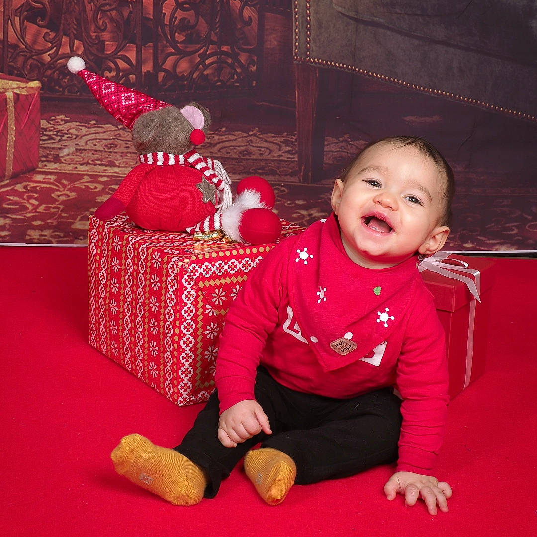 Niméo participe au concours pour gagner de l'argent avec cette photo : baby, baby_toddler_clothing, child, comfort, event, flooring, foot, fun, happy, human_body, human_leg, lap, magenta, person, red, sitting, sleeve, smile, thigh, toddler