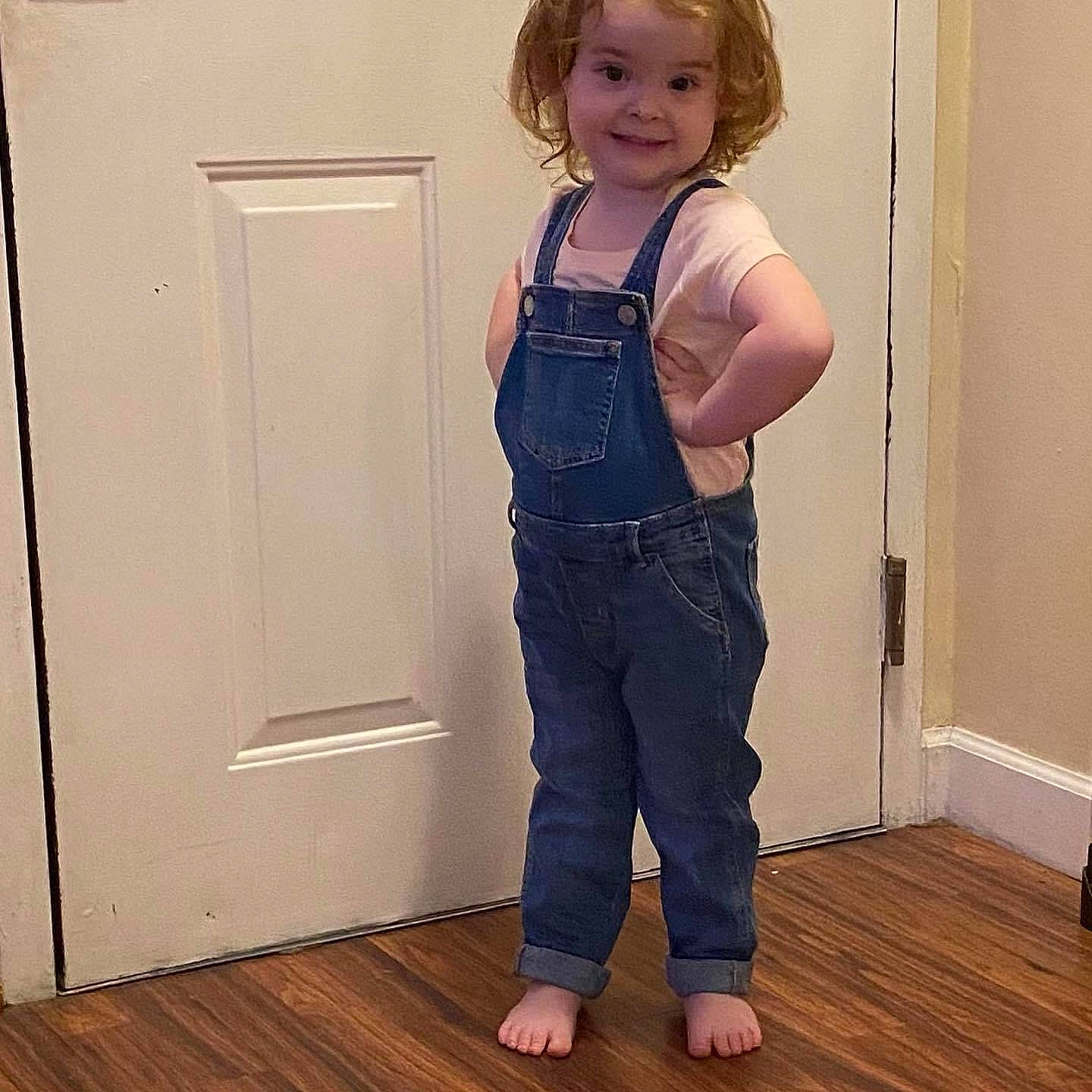 Emma is registered to the contest to win money with this photo: abdomen, baby_toddler_clothing, chest, denim, door, elbow, electric_blue, floor, flooring, hardwood, joy, knee, leg, neck, person, sleeve, smile, standing, thigh, trunk