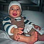 baby, smiling, child, knit_hat, striped_sweater, overalls, bed, blanket, pillow, happy, indoors, person, cute, skin, foot, hand, portrait, sitting, cozy, warm_clothing