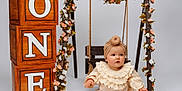 Olivia joined the competition — help win amazing prizes! apple, baby, birthday, celebration, child, cream_clothing, cute, decor, flowers, infant, kneehigh_socks, portrait, props, sitting, smiling, studio, swing, turban, white_background, wooden_blocks