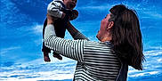 Ekhi a rejoint le concours — aidez-le/la à gagner de superbes lots ! baby, woman, beach, ocean, sky, clouds, smile, joy, holding, denim, striped_shirt, waves, outdoor, portrait, person, happy, child, mother, nature, fun