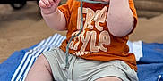 Malone participe au concours pour gagner de l'argent avec cette photo : baby, blanket, blue, child, cute, expression, face, feet, hand, hat, orange_shirt, outdoor, playful, shorts, sitting, smiling, striped, stroller, sun_hat, wooden_wall