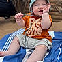 Malone participe au concours pour gagner de l'argent avec cette photo : baby, child, smiling, hat, orange_shirt, shorts, blanket, blue, striped, sitting, outdoor, face, hand, feet, expression, cute, playful, sun_hat, stroller, wooden_wall