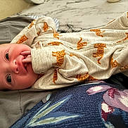 Dutton joined the competition — help win amazing prizes! baby, infant, onesie, tiger_print, hand, face, eyes, blanket, cushion, fabric, lying_down, cozy, cute, newborn, skin, small_fingers, bed, soft, comfort, portrait
