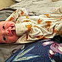 baby, infant, onesie, tiger_print, hand, face, eyes, blanket, cushion, fabric, lying_down, cozy, cute, newborn, skin, small_fingers, bed, soft, comfort, portrait