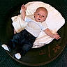Dominic joined the competition — help win amazing prizes! baby, infant, child, tire, blanket, white_shirt, jeans, socks, indoor, laying, cute, face, expression, small_hands, small_feet, soft_texture, dark_background, round_object, relaxed, pose