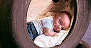 Dominic joined the competition — help win amazing prizes! baby, tire, blanket, infant, clothing, jeans, white_shirt, face, head, lying_down, soft_texture, curious_expression, outdoor, closeup, portrait, child, cushion, resting, round_shape, hoosier