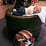 Dominic joined the competition — help win amazing prizes! baby, sleeping, pacifier, blanket, tire, helmet, motorcycle_helmet, jeans, white_shirt, garage, floor, person, infant, indoor, resting, headwear, clothing, soft, cute, relaxation