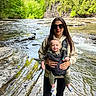 Jaxon joined the competition — help win amazing prizes! baby, baby_carrier, casual, clothing, daylight, forest, greenery, happy, nature, outdoor, person, river, rocks, scenic, smile, standing, sunglasses, trees, water, woman