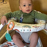 Jaxon is registered to the contest to win money with this photo: baby, carpet, child, colorful, comfort, curious, cute, expression, face, green_clothing, home, indoor, infant, person, play, seated, socks, toy, walker, young