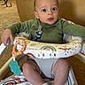 baby, carpet, child, colorful, comfort, curious, cute, expression, face, green_clothing, home, indoor, infant, person, play, seated, socks, toy, walker, young
